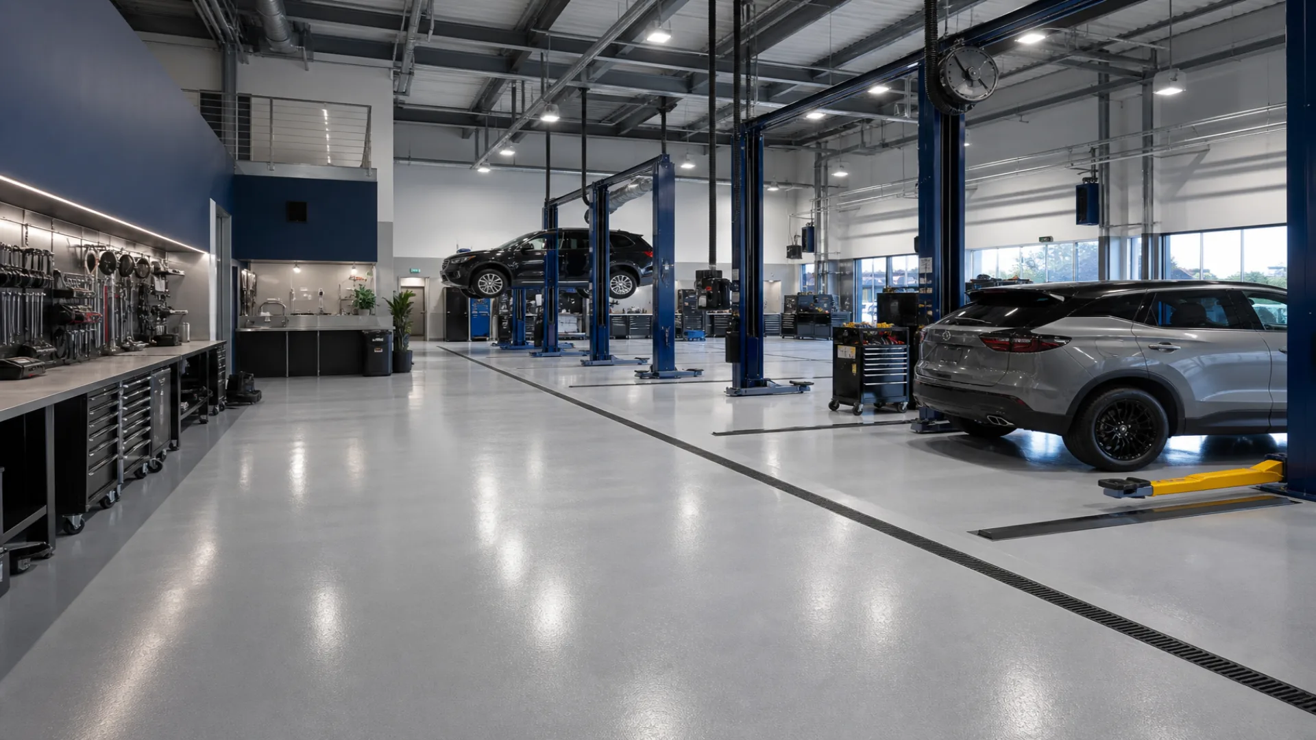 Wide view of a clean auto repair workshop floor with organized tool stations and vehicle lift bays, 1920x1080